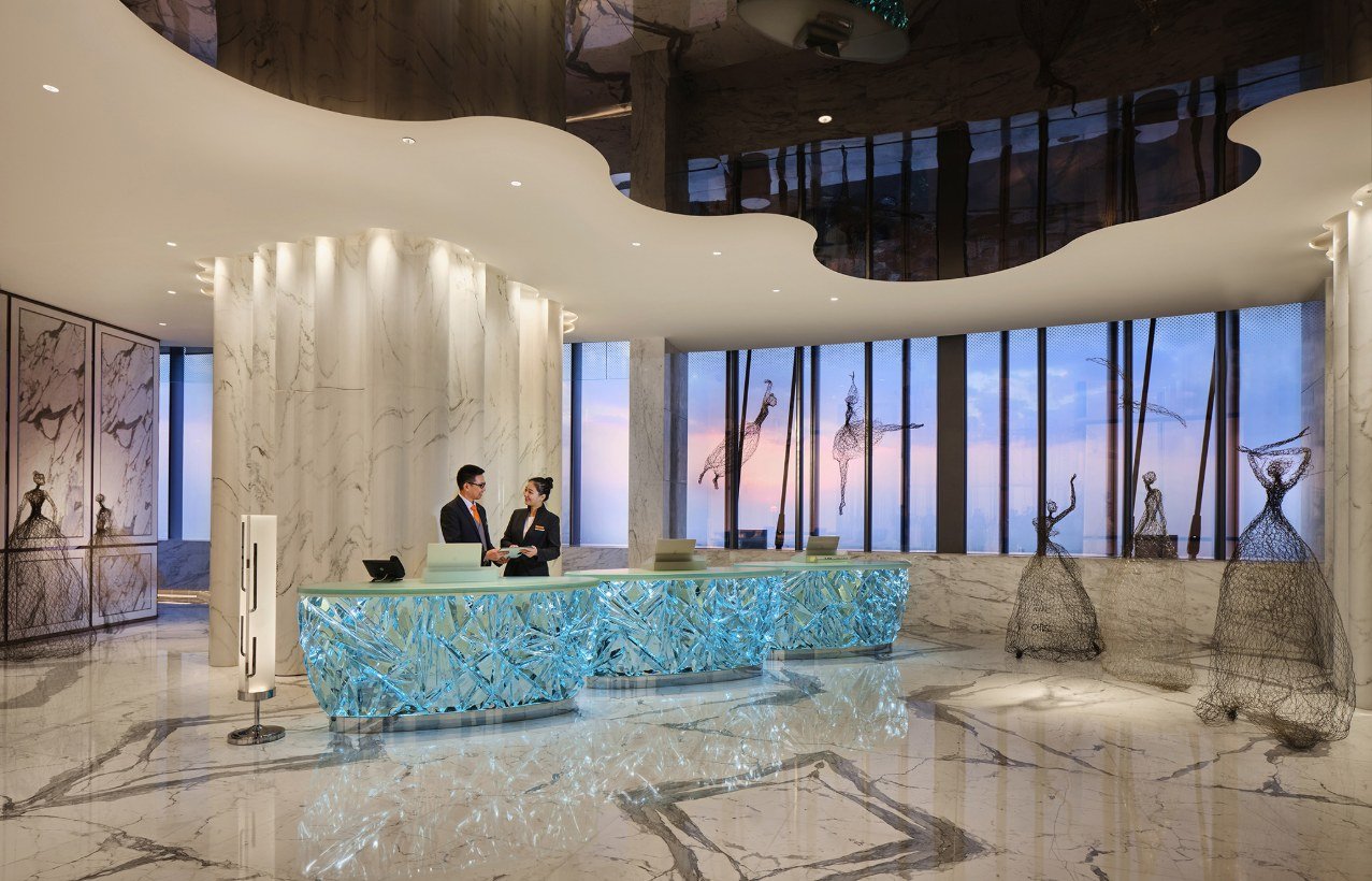 El mostrador de recepción del J Hotel Shanghai Tower está rodeado de mármol y candelabros.